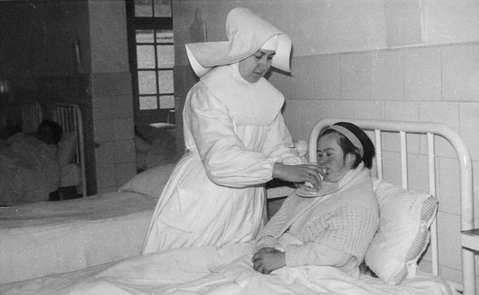 una hermana hospitalaria atiende a una mujer con discapacidad en el antiguo hospital de aita menni