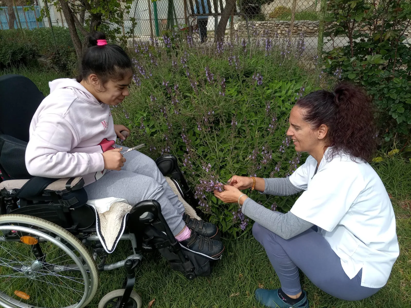 trabajadora de hospitalarias fundación purísima concepción ayuda a una niña con discapacidad en silla de ruedas