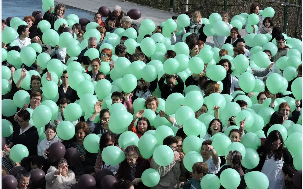 grupo numeroso de personas con globos verdes y negros