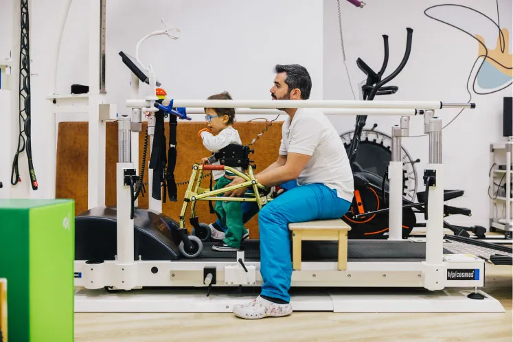 un fisioterapia de fundación hospitalarias valencia ayuda a un niño con movilidad reducida a caminar sobre una cinta
