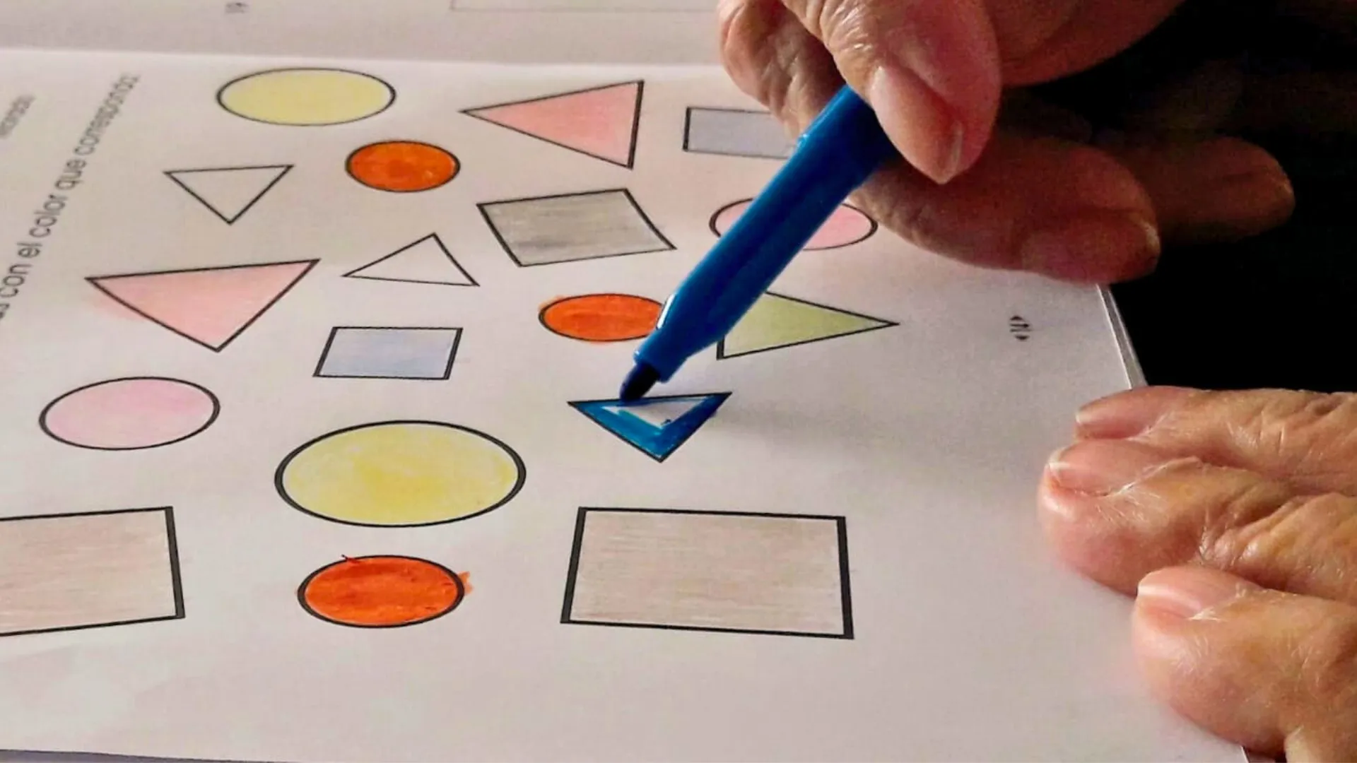 manos de una persona con discapacidad coloreando figuras geométricas