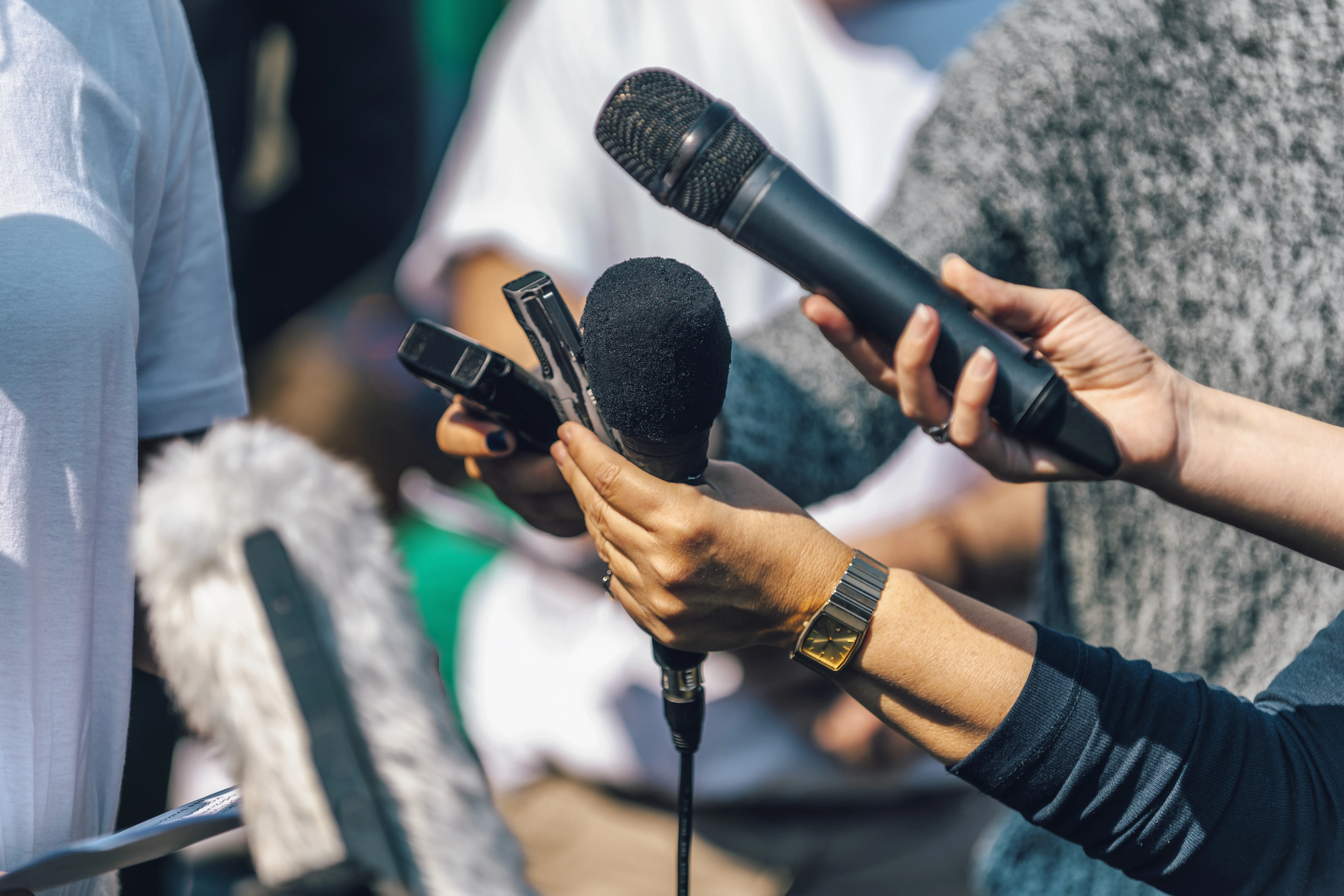 manos que sujetan micrófonos de prensa