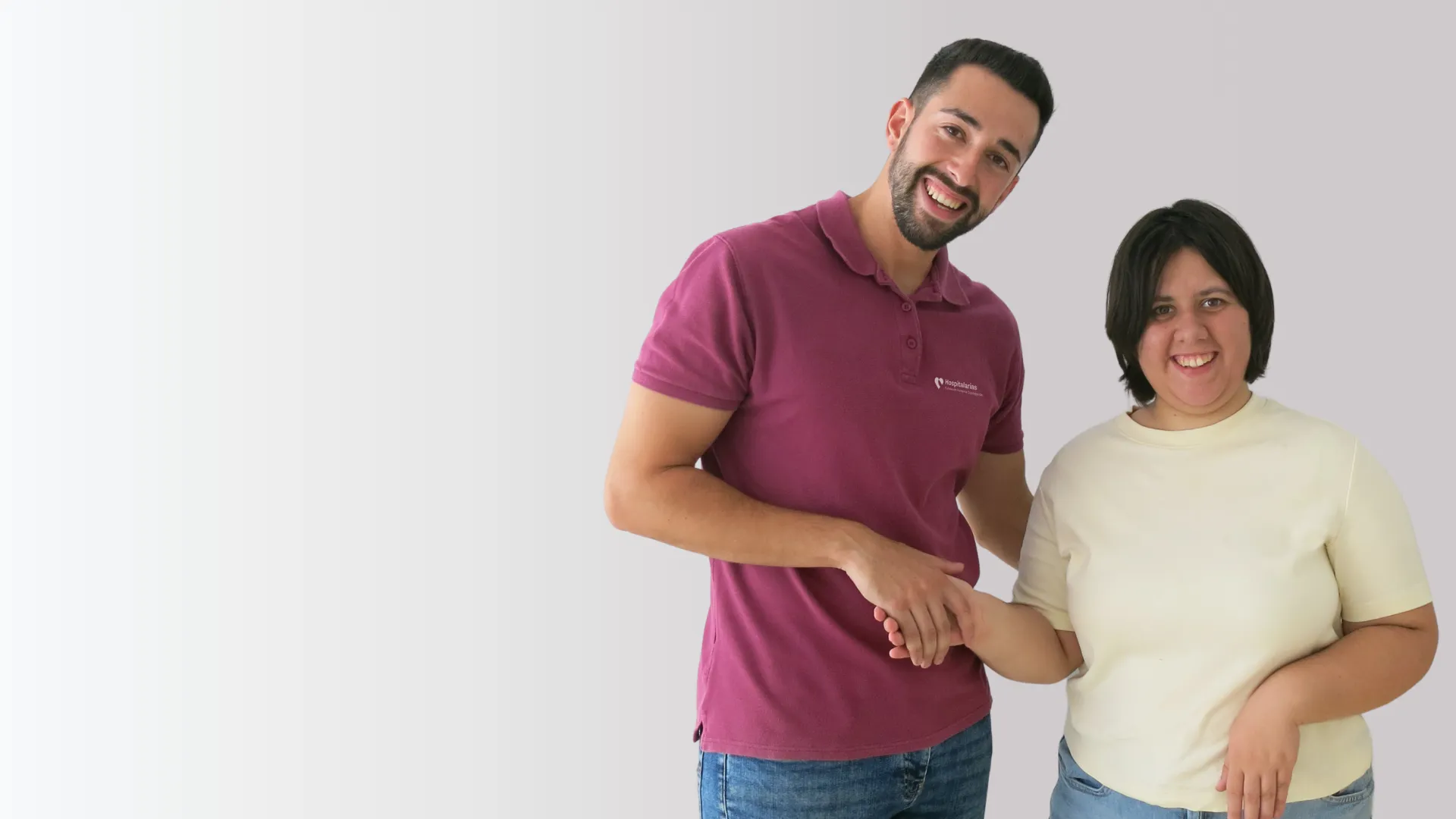 trabajador y usuaria de la Hospitalarias Fundación Purísima Concepción se dan la mano en actitud amistosa y miran sonriendo a cámara