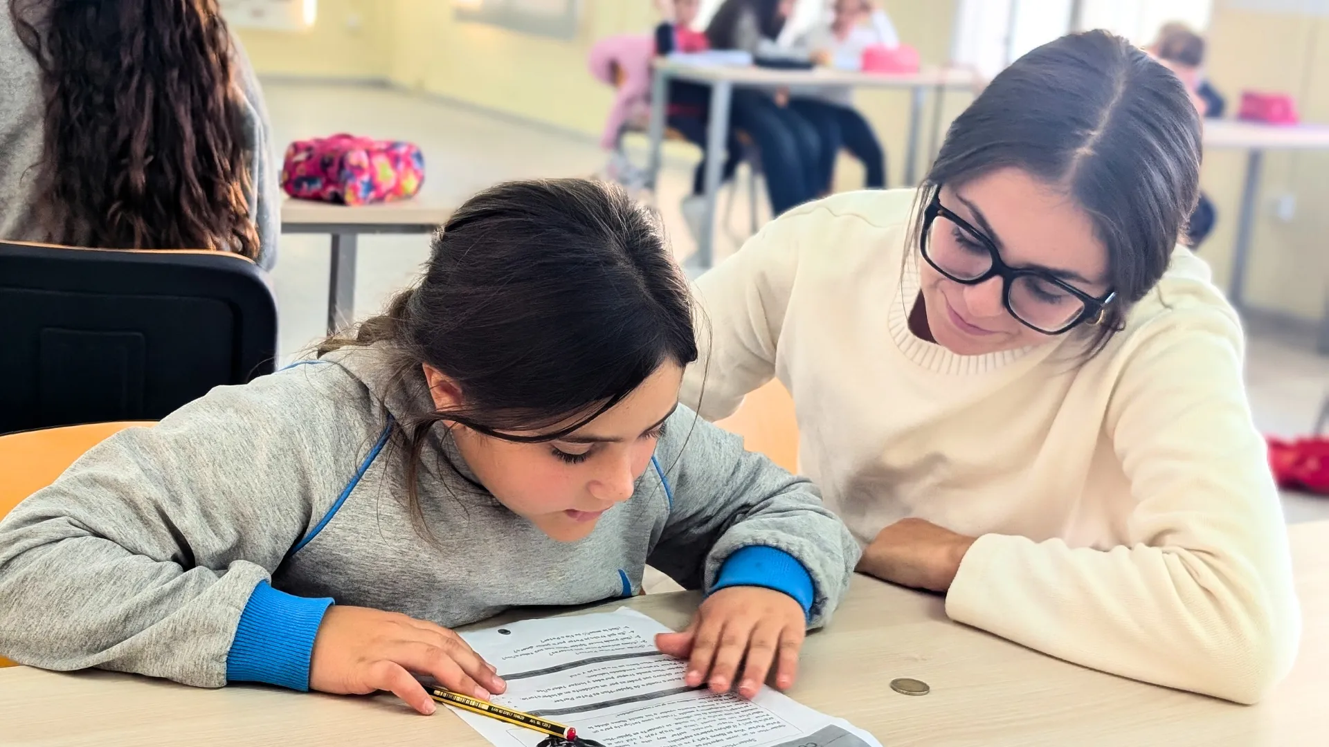 voluntaria de la Fundación Hospitalarias ayuda a leer a una niña con discapacidad