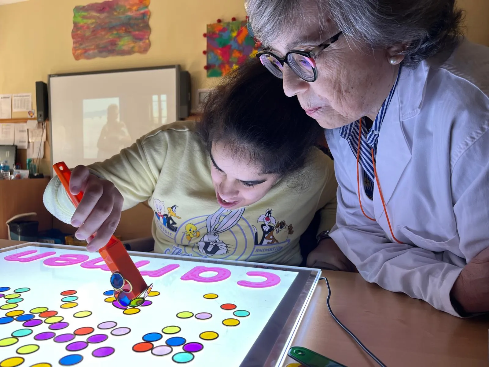 voluntaria de la fundación hospitalarias con una niña con discapacidad juegan a un juego de mesa