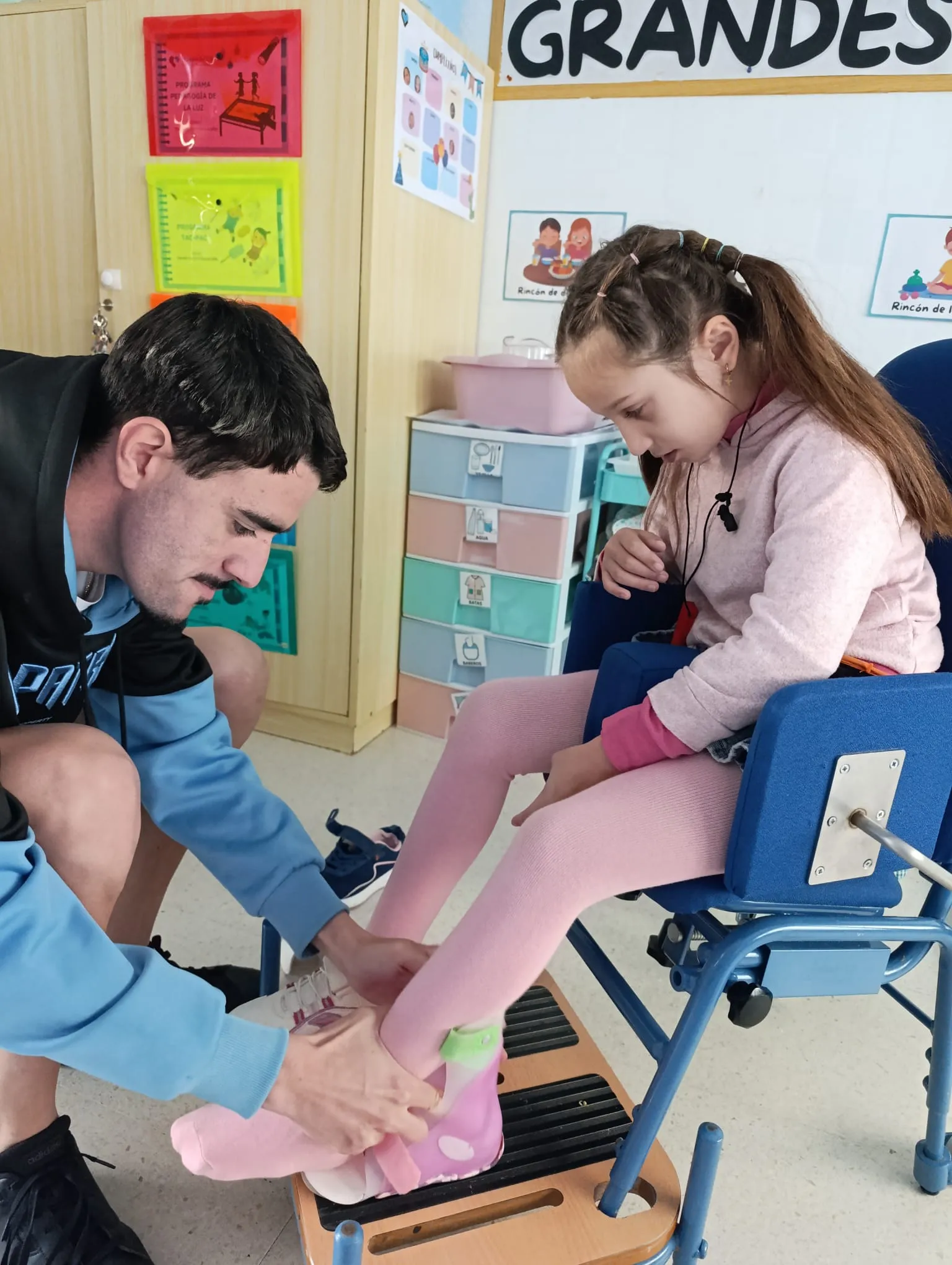 voluntario ayuda a una niña a ponese los zapatos