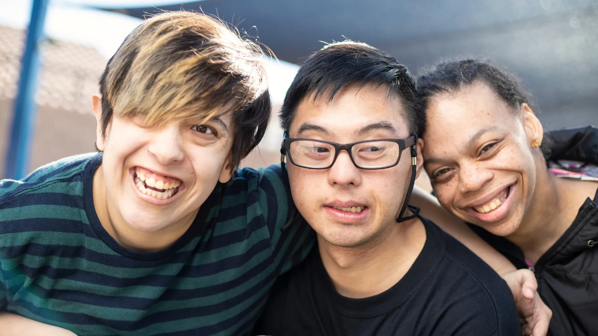 tres personas con discapacidad intelectual miran a cámara sonriendo