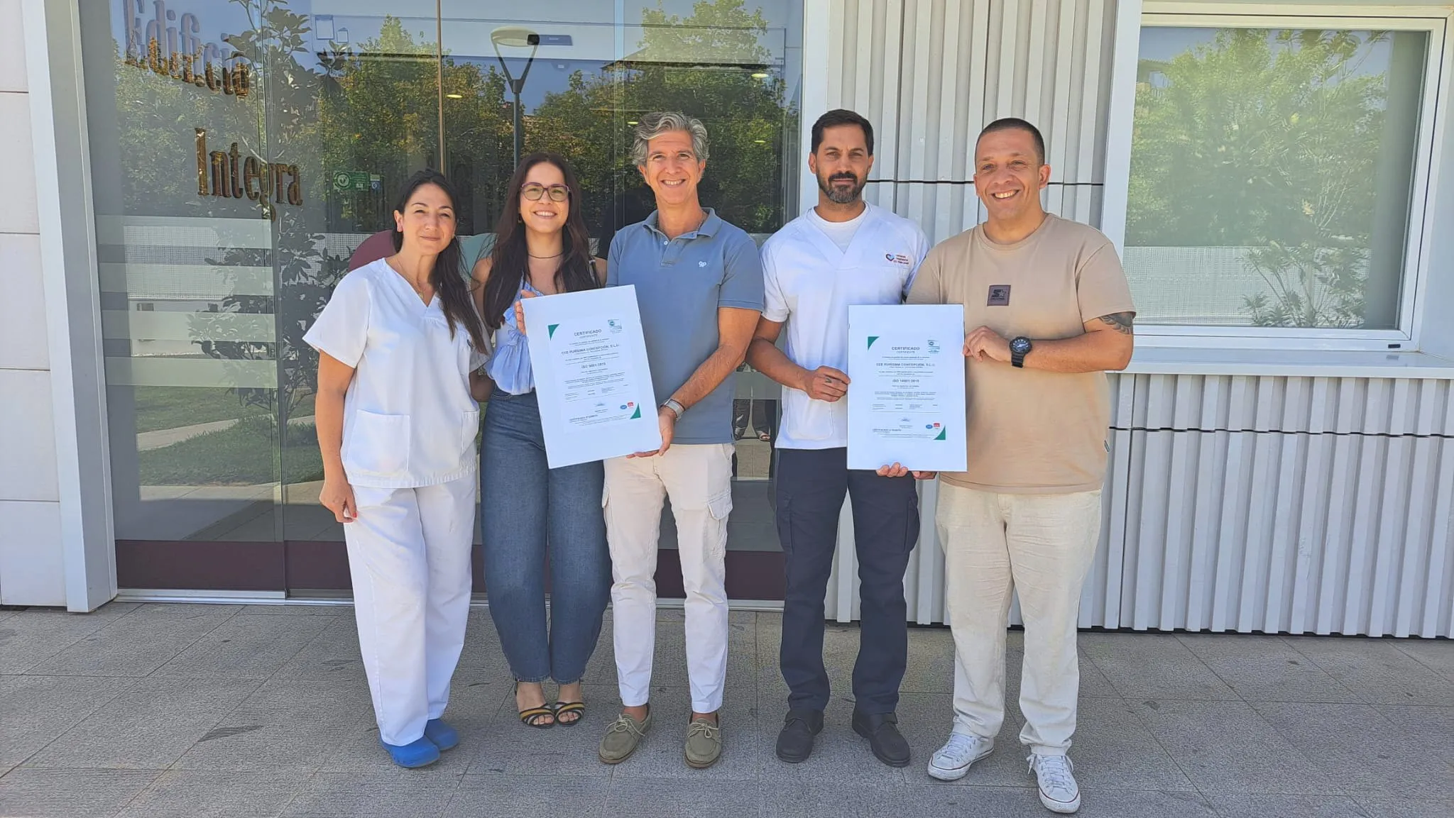 un grupo de personas sostiene las certificaciones ISO 9001 e ISO 14001 en Hospitalarias Fundación Purísima Concepción